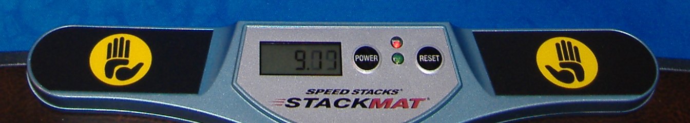 Primer plano de un Stackmat con la pantalla marcando 9.09 y los dos pads con la mano amarilla a los costados.